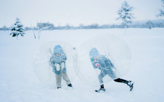 Children playing in snow inside inflatable bubbles during Sapporo to Bibai Snow Land tour, Hokkaido.