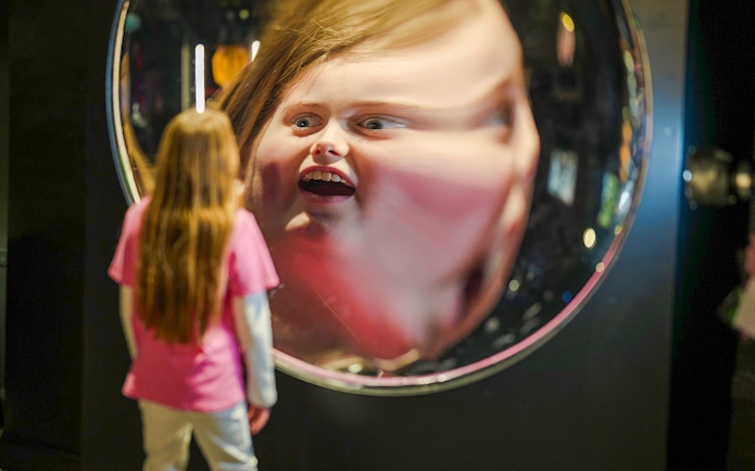 Child viewing reflection in parabolic mirror at Camera Obscura & World of Illusions, Edinburgh.