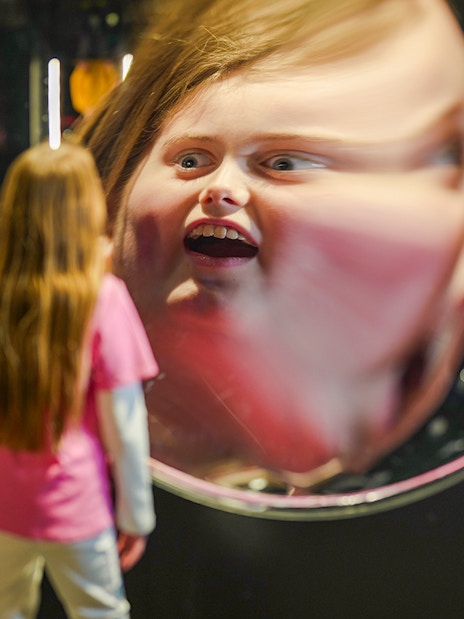 Child viewing reflection in parabolic mirror at Camera Obscura & World of Illusions, Edinburgh.