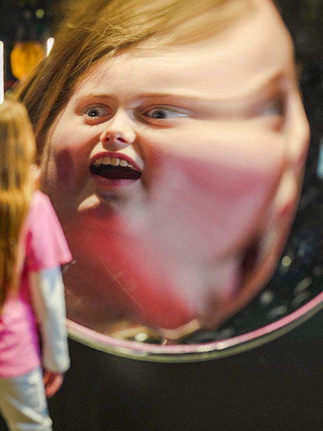 Child viewing reflection in parabolic mirror at Camera Obscura & World of Illusions, Edinburgh.