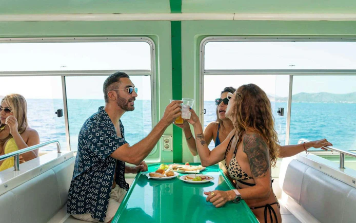 Tourists enjoying lunch on Ibiza to Formentera cruise with ocean view.