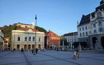 Ljubljana city square with Ljubljana Castle in the background, people exploring the area.