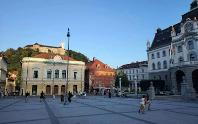 Ljubljana city square with Ljubljana Castle in the background, people exploring the area.