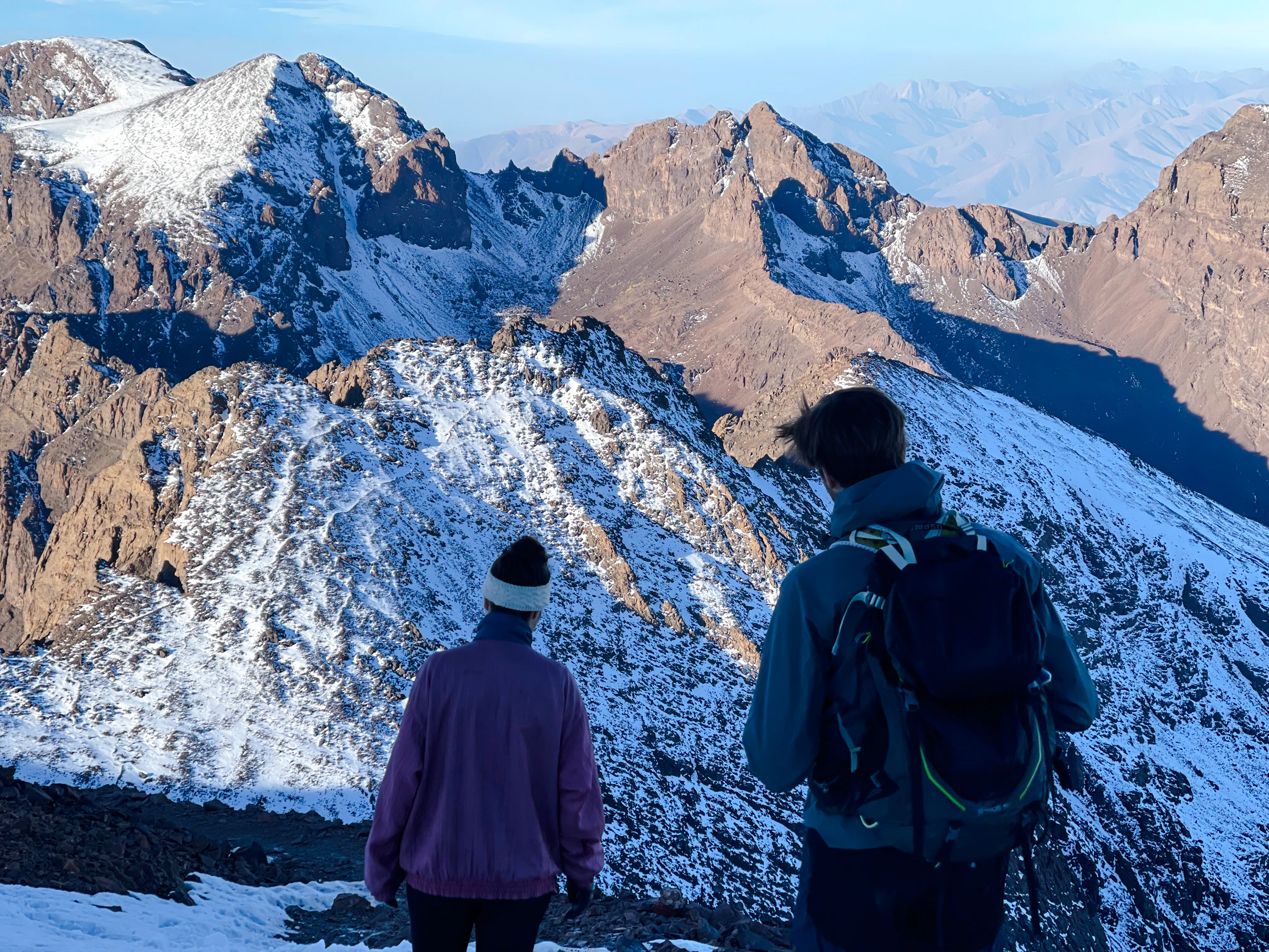 Two hikers overlooking snow-capped peaks during Mount Toubkal trek from Marrakech.