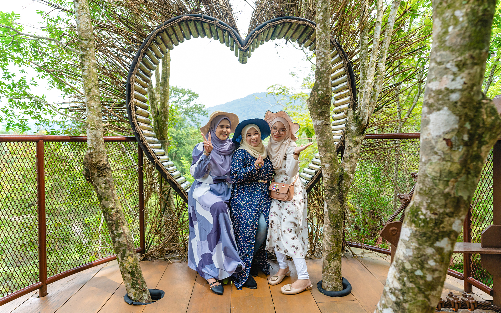 Three people posing in front of a heart-shaped structure at Crocodile Adventureland Langkawi.