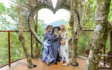 Three people posing in front of a heart-shaped structure at Crocodile Adventureland Langkawi.