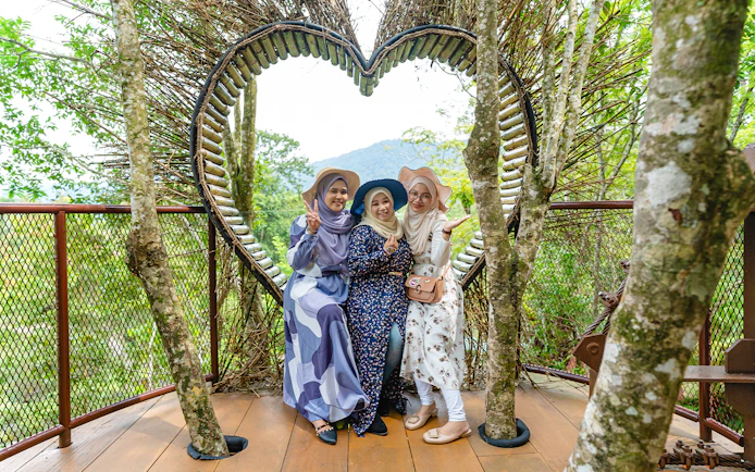 Three people posing in front of a heart-shaped structure at Crocodile Adventureland Langkawi.