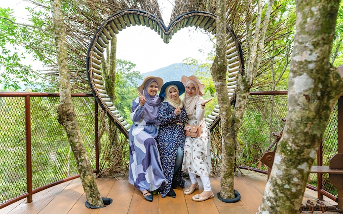 Three people posing in front of a heart-shaped structure at Crocodile Adventureland Langkawi.