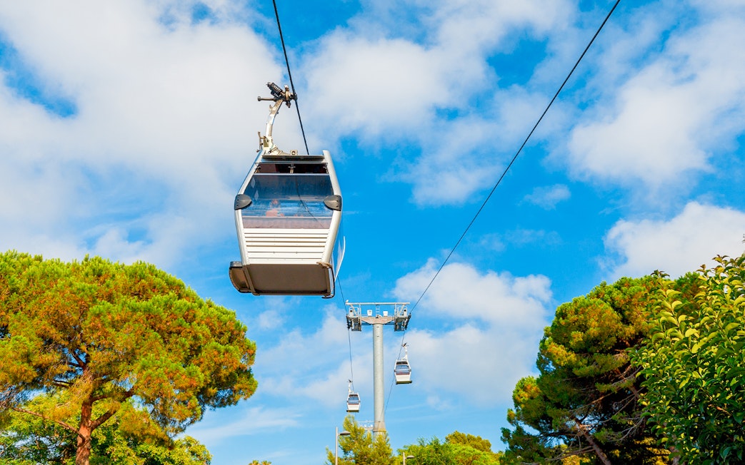 Cable cars ascending Montjuic in Barcelona, Spain against a blue sky.