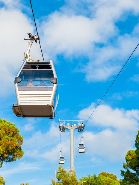 Cable cars ascending Montjuic in Barcelona, Spain against a blue sky.