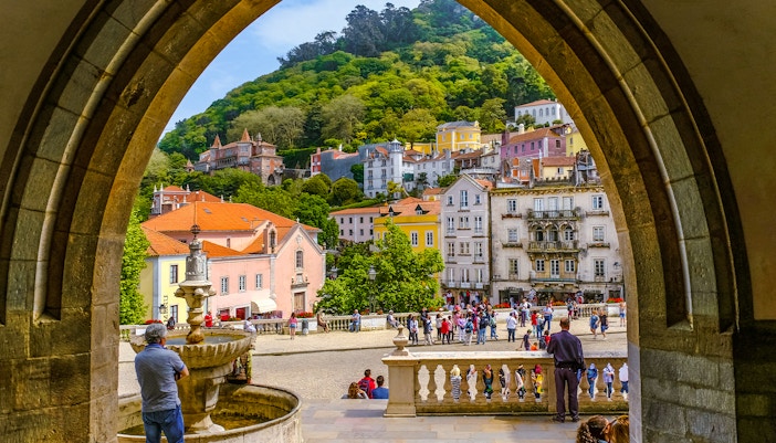 View of Sintra town square through an archway, featuring colorful buildings and a fountain.