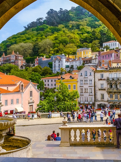 View of Sintra town square through an archway, featuring colorful buildings and a fountain.