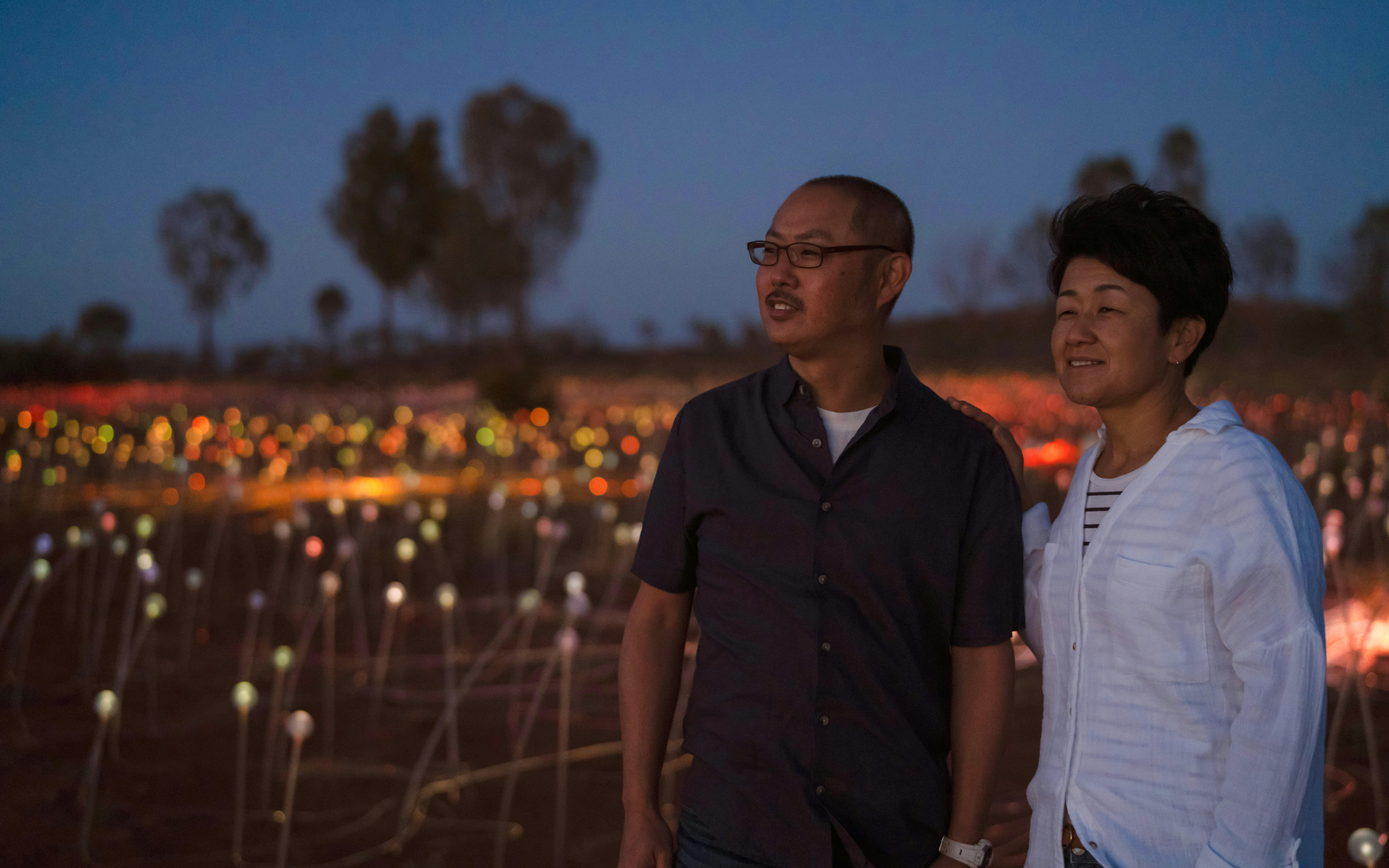 Couple enjoying Uluru's Field of Light installation at sunrise.