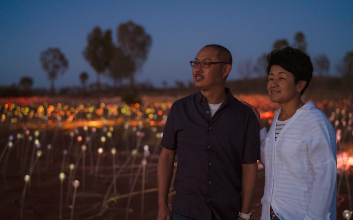Couple enjoying Uluru's Field of Light installation at sunrise.