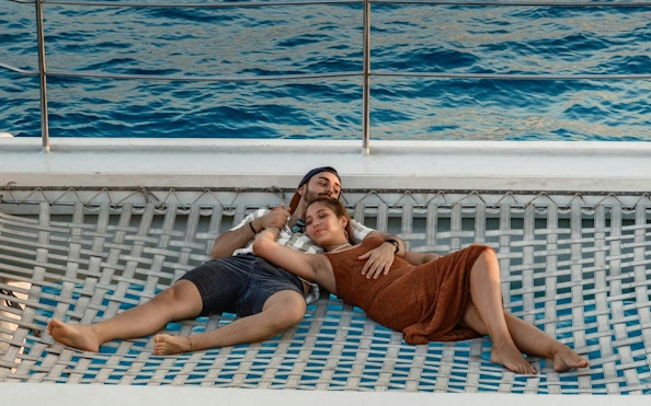 Couple relaxing on a boat net at sunset in Mallorca.