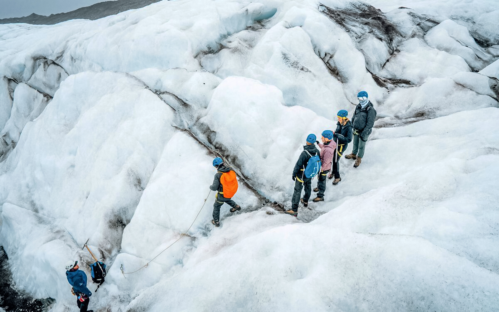 Tour guide leading group through ice maze and glacier crevasse.