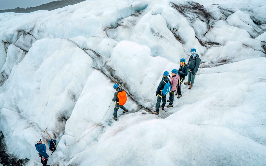 Tour guide leading group through ice maze and glacier crevasse.