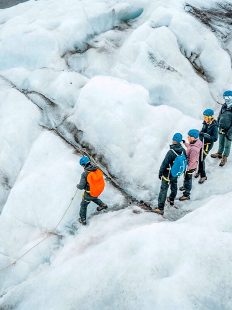 Tour guide leading group through ice maze and glacier crevasse.