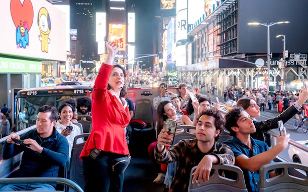 Tour guide speaking to tourists on a New York Hop On Hop Off bus in Times Square.