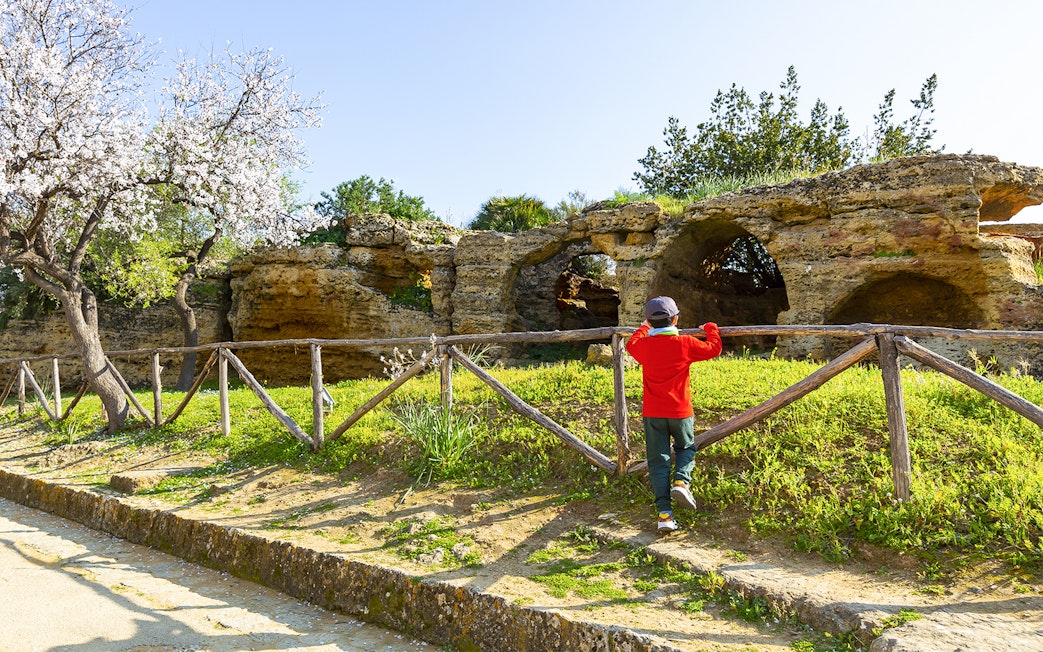Child exploring ancient caves in Valley of the Temples, Kolymbethra, Sicily.