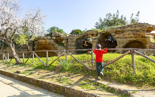 Child exploring ancient caves in Valley of the Temples, Kolymbethra, Sicily.