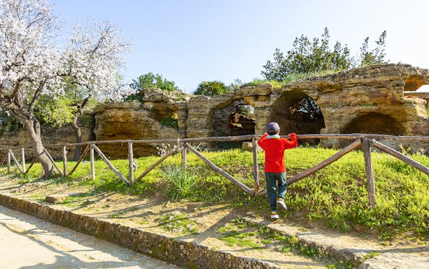 Child exploring ancient caves in Valley of the Temples, Kolymbethra, Sicily.