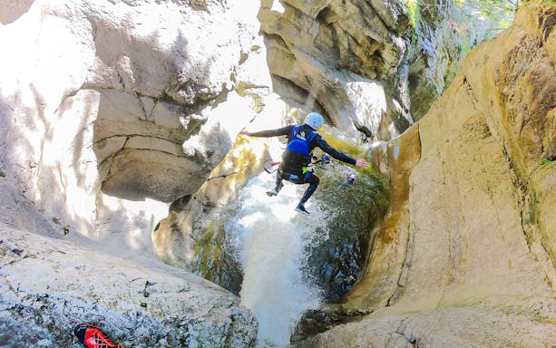 Adventurers canyoning through a narrow gorge in Interlaken, Switzerland, navigating rocky terrain and cascading waterfalls.