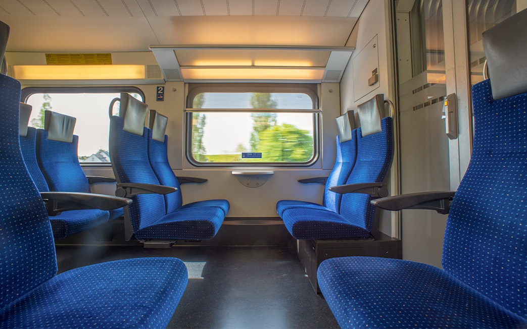 Passenger seats on Bernina train with scenic window view.