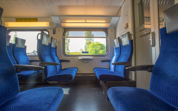Passenger seats on Bernina train with scenic window view.