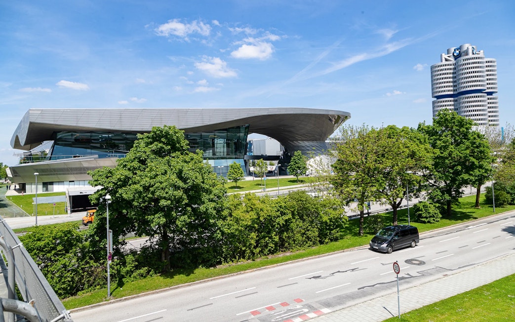 Munich BMW Welt and BMW Tower seen from the street on a sunny day.