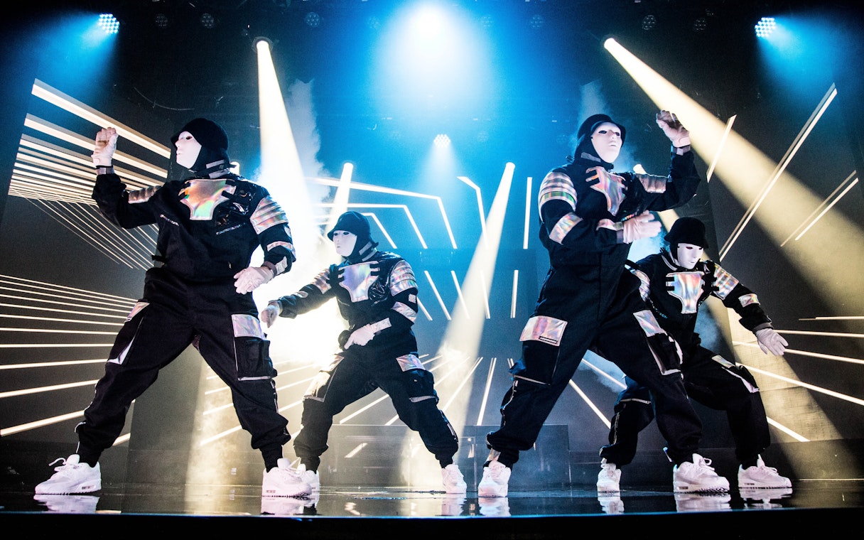 Dancers performing at Jabbawockeez show in Las Vegas with dynamic lighting effects.