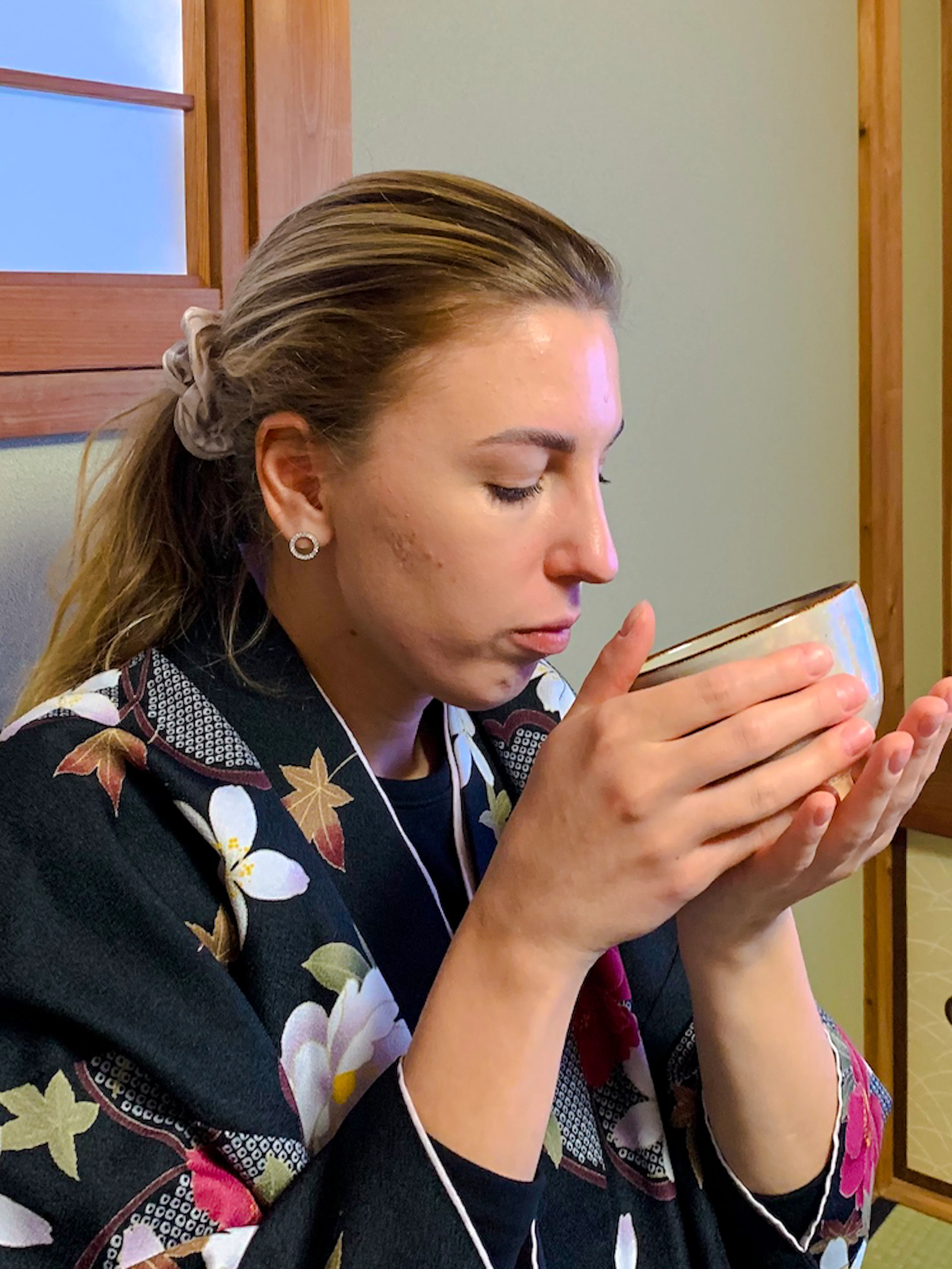 Woman participating in a traditional tea ceremony in Kyoto, holding a tea bowl.