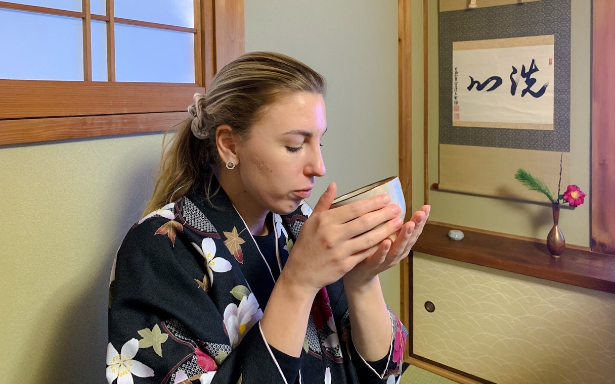 Woman participating in a traditional tea ceremony in Kyoto, holding a tea bowl.