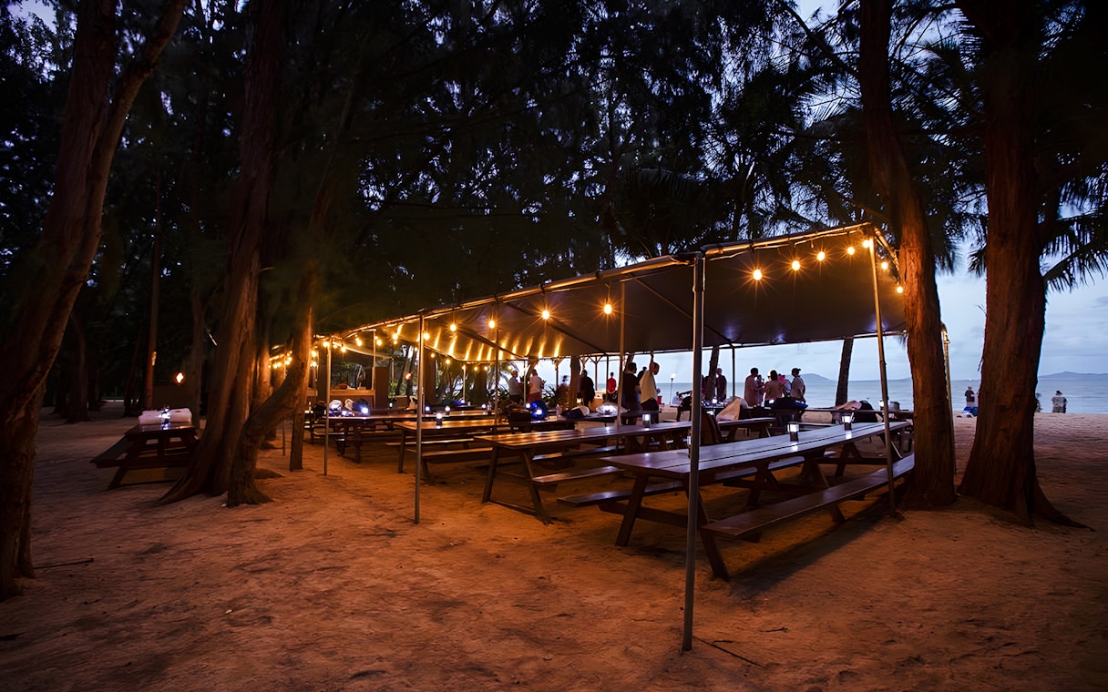 Outdoor dining setup with string lights at Secret Island Beach, Kualoa Ranch, Hawaii.