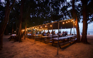 Outdoor dining setup with string lights at Secret Island Beach, Kualoa Ranch, Hawaii.