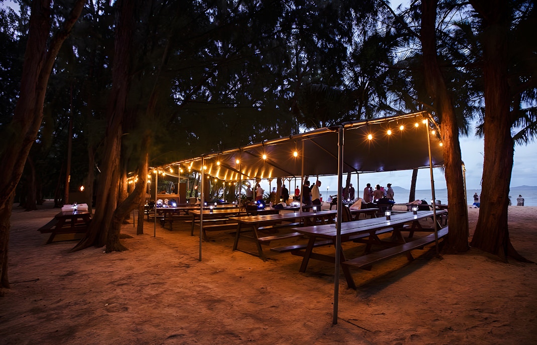 Outdoor dining setup with string lights at Secret Island Beach, Kualoa Ranch, Hawaii.