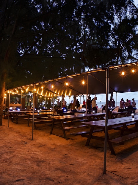 Outdoor dining setup with string lights at Secret Island Beach, Kualoa Ranch, Hawaii.