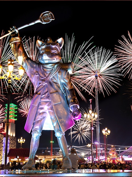 Fireworks over Global Village Dubai with large statue and Ferris wheel.