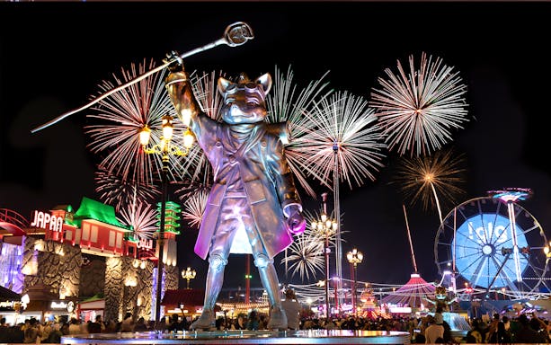 Fireworks over Global Village Dubai with large statue and Ferris wheel.