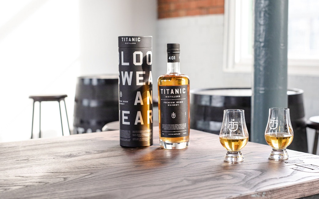 Titanic Distillers whiskey bottle and glasses on a wooden table for tasting experience.