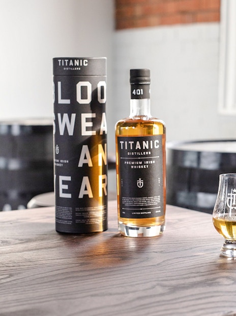 Titanic Distillers whiskey bottle and glasses on a wooden table for tasting experience.