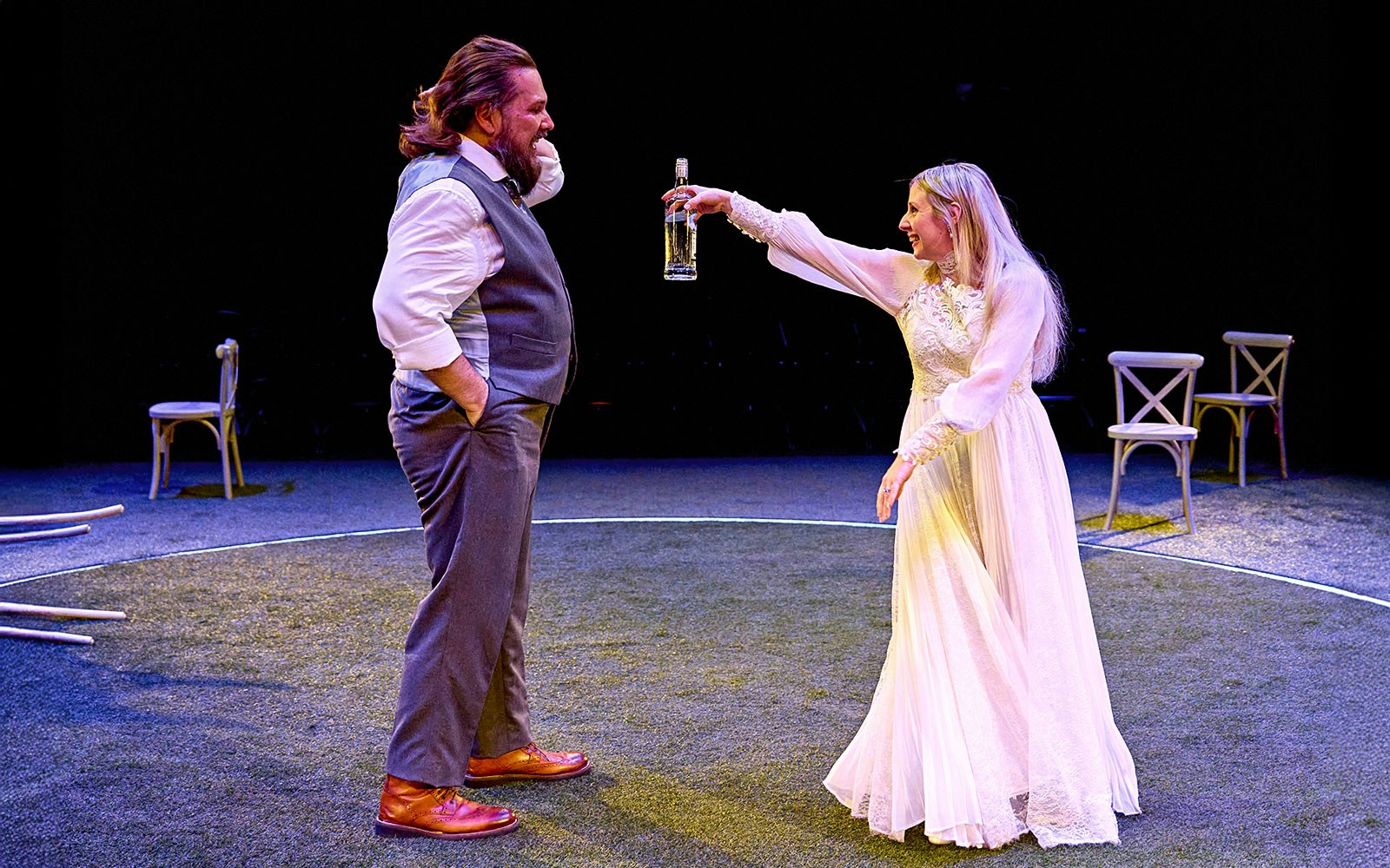 Man and woman performing on stage with a bottle, part of "Till The Stars Come Down" show.