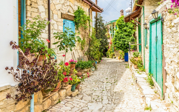 Traditional stone street with colorful flowers in Lania village, Cyprus.