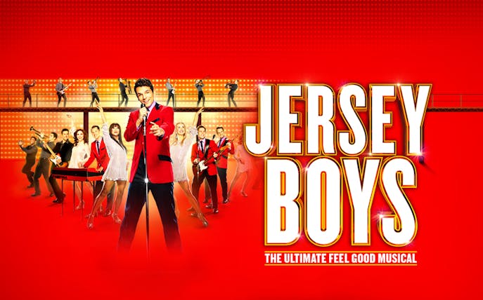 Jersey Boys musical cast performing on stage with bright lights and instruments.