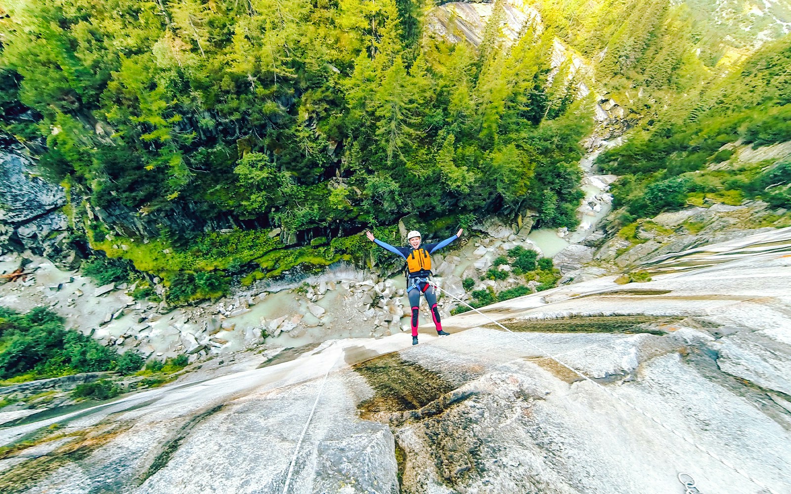 Adventurers canyoning through a narrow gorge in Interlaken, Switzerland, navigating waterfalls and rocky terrain.