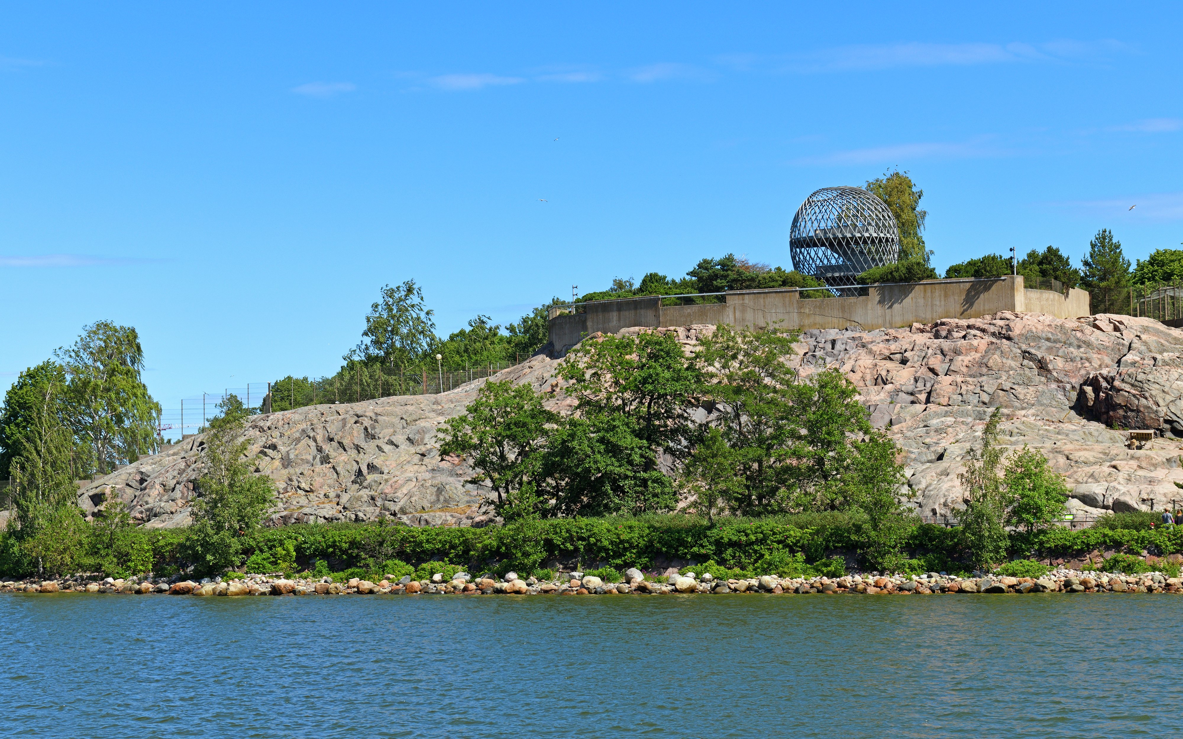 Helsinki Zoo view from the sea with rocky shoreline and greenery, Finland.