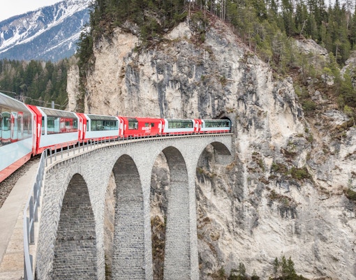 Train crossing Landwasser Viaduct in Swiss Alps, connecting Zermatt and St. Moritz.