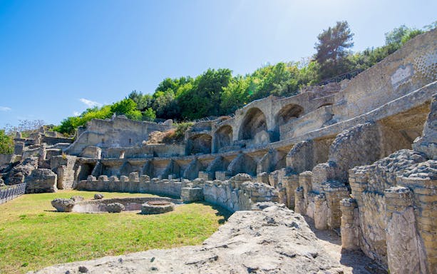 Ruins of the Archaeological Park of the Baths of Baiae, Naples, Italy, with ancient stone arches and greenery.