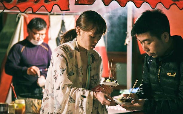 People enjoying street food during a guided tour of Kyoto's lanes and lanterns.