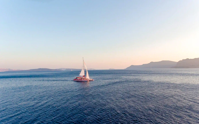 Catamaran sailing on the sea during the Red Cruise near Santorini.